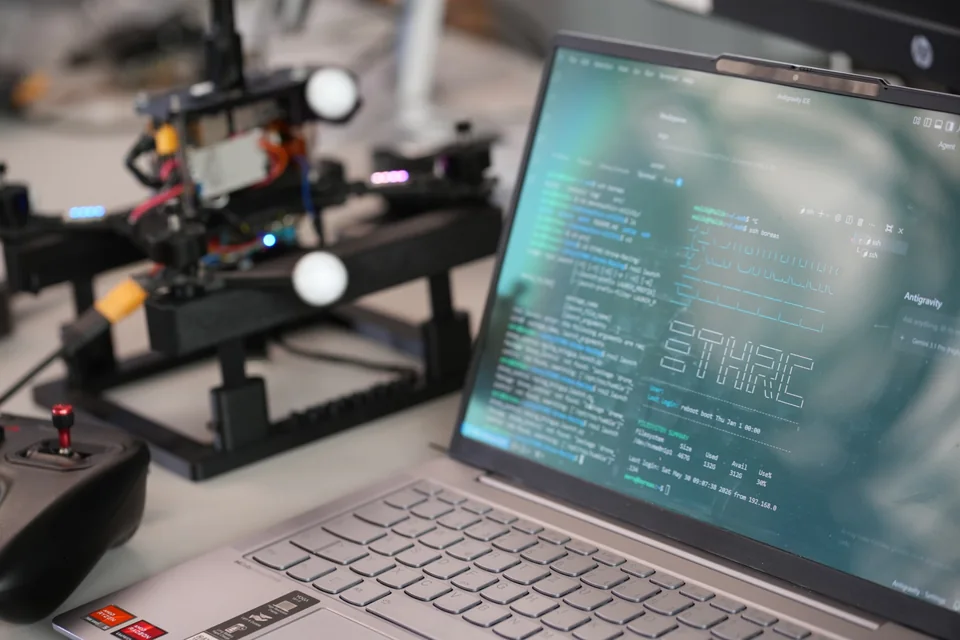 A laptop running robotics software beside a drone test rig